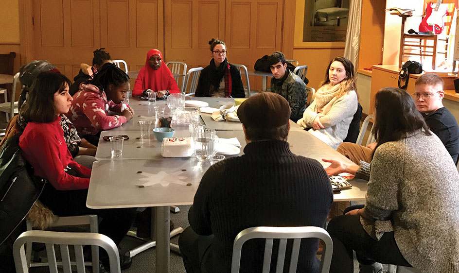 High school student refugees in discussion around a large table at City Theatre.
