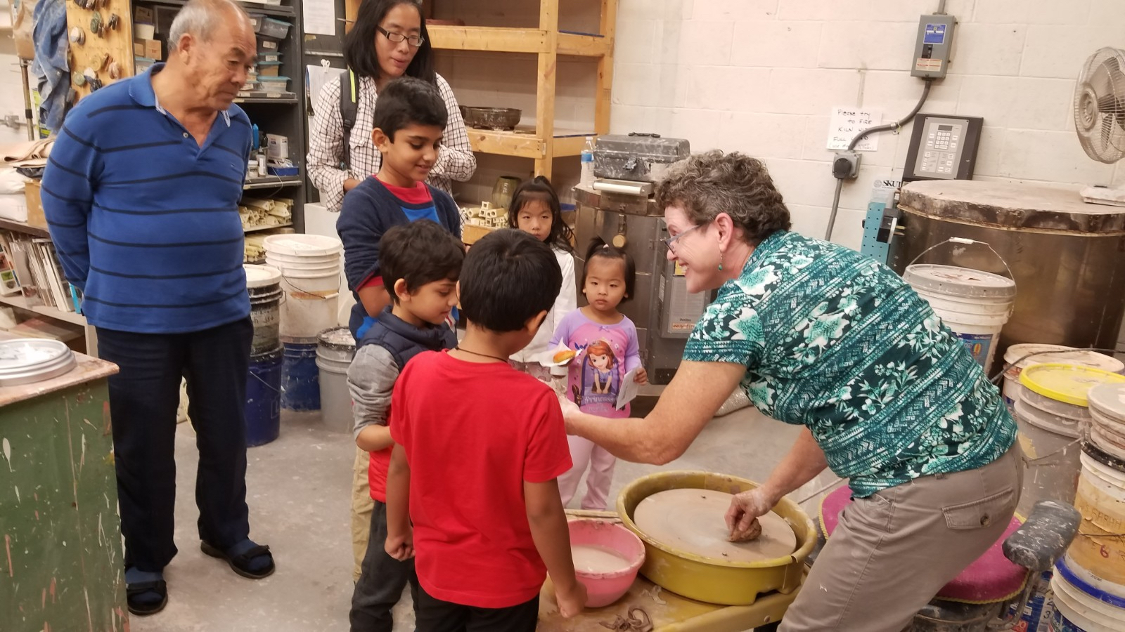 Women speaking to children in a pottery class.