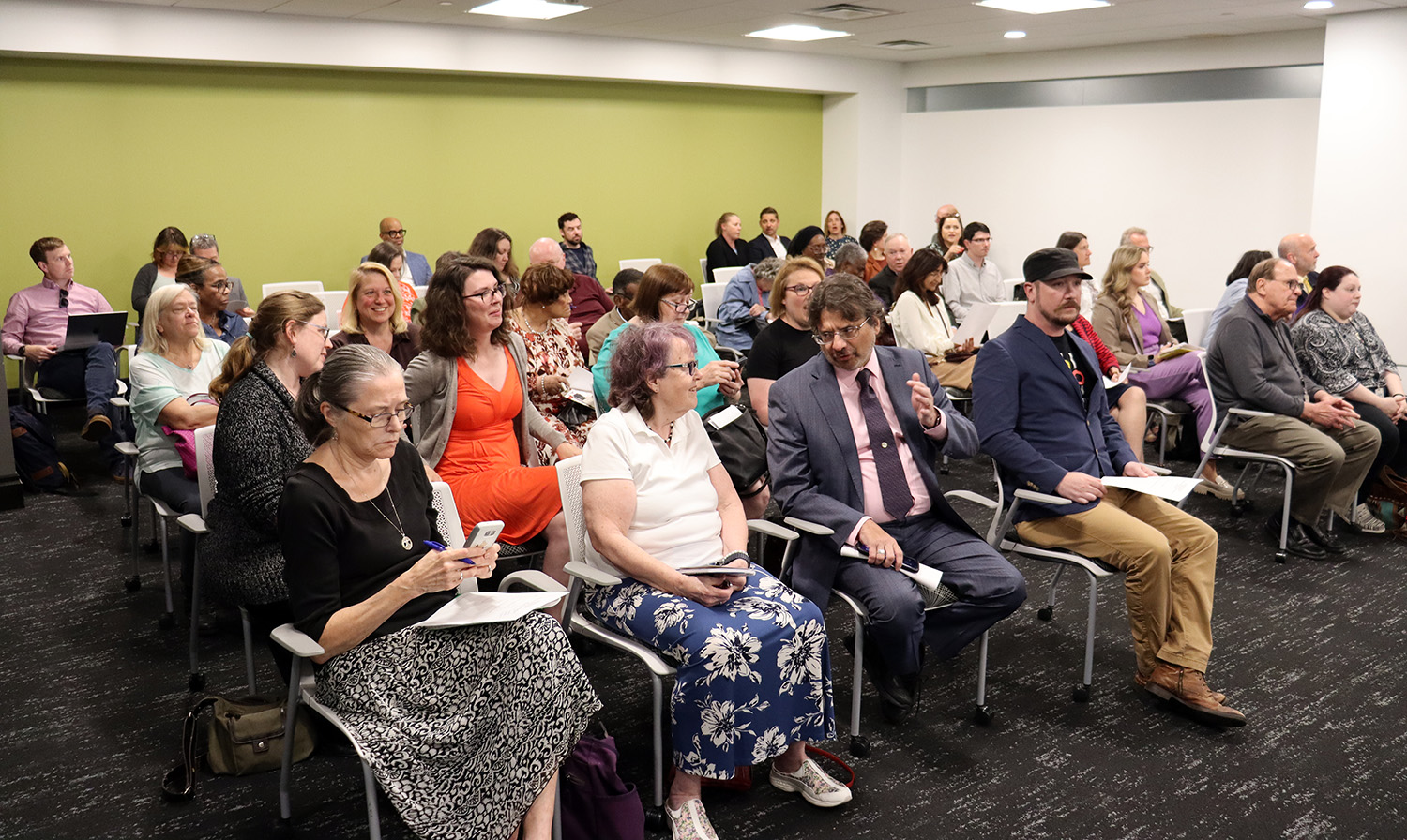 A large crowd is seen sitting and talking in a conference room