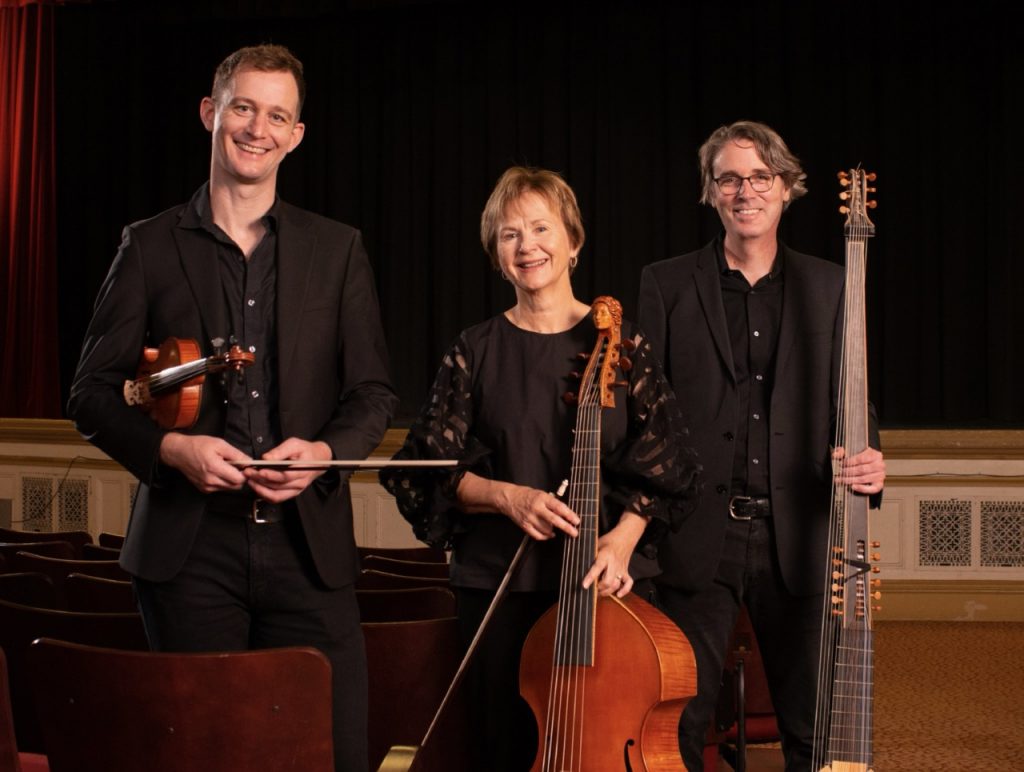Photograph of Chatham Baroque’s Andrew Fouts (violin), Patricia Halverson (viola da gamba), and Scott Pauley (theorbo) posing with their instruments