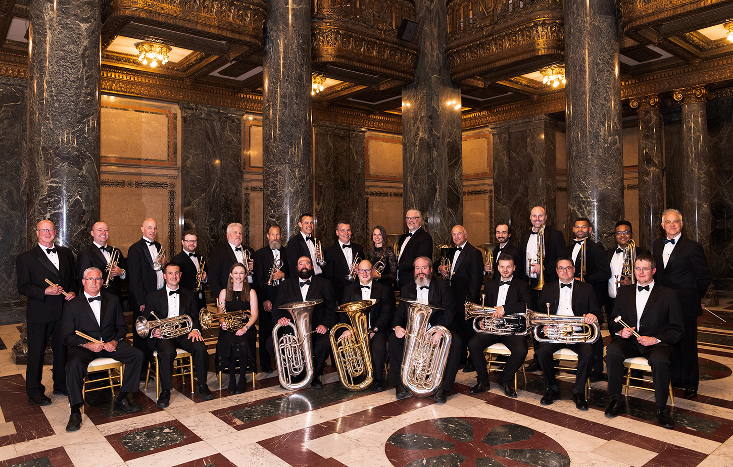 Brass band seated in tuxedoes with their instruments