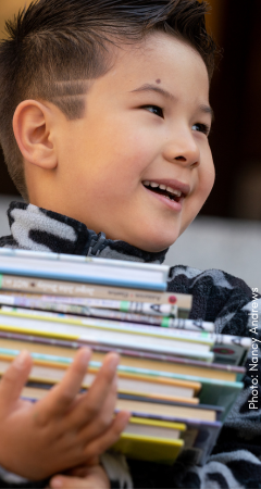 Little boy with a stack of library books
